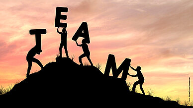 Silhouette, Teamarbeit von Männern, die helfen und das Wort TEAM zu heben