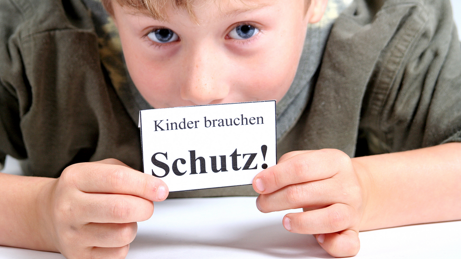 Foto: AdobeStock/Yvonne Bogdanski Kind hält ein Schild mit der Aufschrift "Kinder brauchen Schutz" hoch